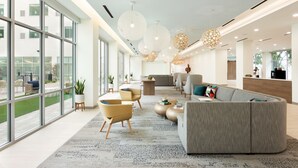 A modern lobby with large windows, a grey sofa, and a coffee table.