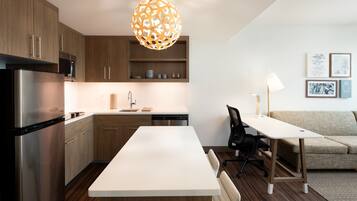 Una cocina moderna con armarios de madera, un refrigerador de acero inoxidable, una encimera blanca y una lámpara colgante.