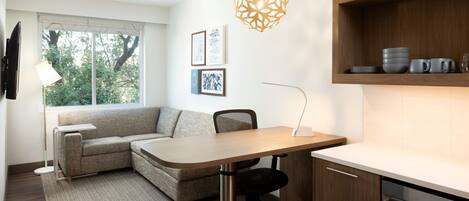Una sala de estar moderna con un sofá, una mesa de comedor y una zona de cocina con un estante de madera.