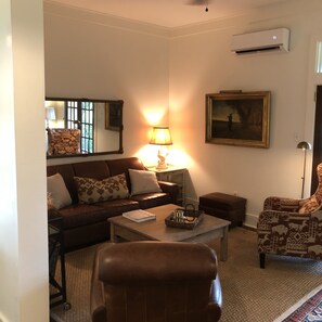 Relax in this inviting living room with a comfortable sofa, armchair, and coffee table, featuring a beautiful painting and a cozy rug.