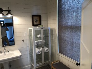 Enjoy a clean and functional bathroom with a large mirror, sink, and glass-fronted cabinet.