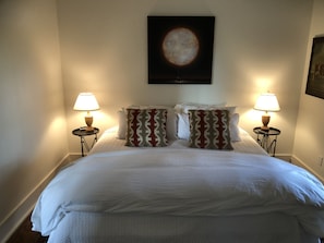 Relax in comfort with a large bed, two nightstands, and a framed artwork above.