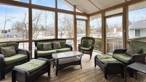 A covered outdoor seating area with wicker furniture and large windows. - Pool, Outdoor living, 100 yards from Lake Michigan! (New Buffalo)