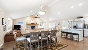 A spacious living room with a fireplace, a dining area with a large table and chairs, a kitchen with modern appliances, and a ceiling fan. - Pool, Outdoor living, 100 yards from Lake Michigan! (New Buffalo)