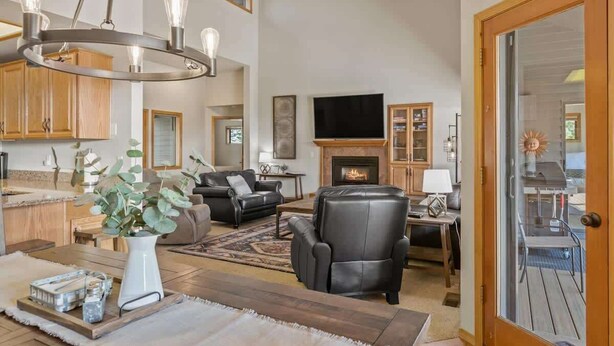 A spacious living room with a fireplace, leather furniture, and a large chandelier. - AC, Hot Tub, One level, Pet friendly (Sunriver)