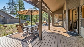 A covered patio with a table and chairs, a large umbrella, and a view of the surrounding landscape. - AC, Hot Tub, One level, Pet friendly (Sunriver)