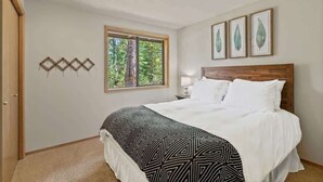 A bedroom with a bed, a window with a view of trees, and three framed leaf artworks on the wall. - AC, Hot Tub, One level, Pet friendly (Sunriver)