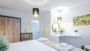 Une chambre à coucher moderne avec un grand lit, une armoire en bois, un miroir et une étagère murale décorée de fleurs.