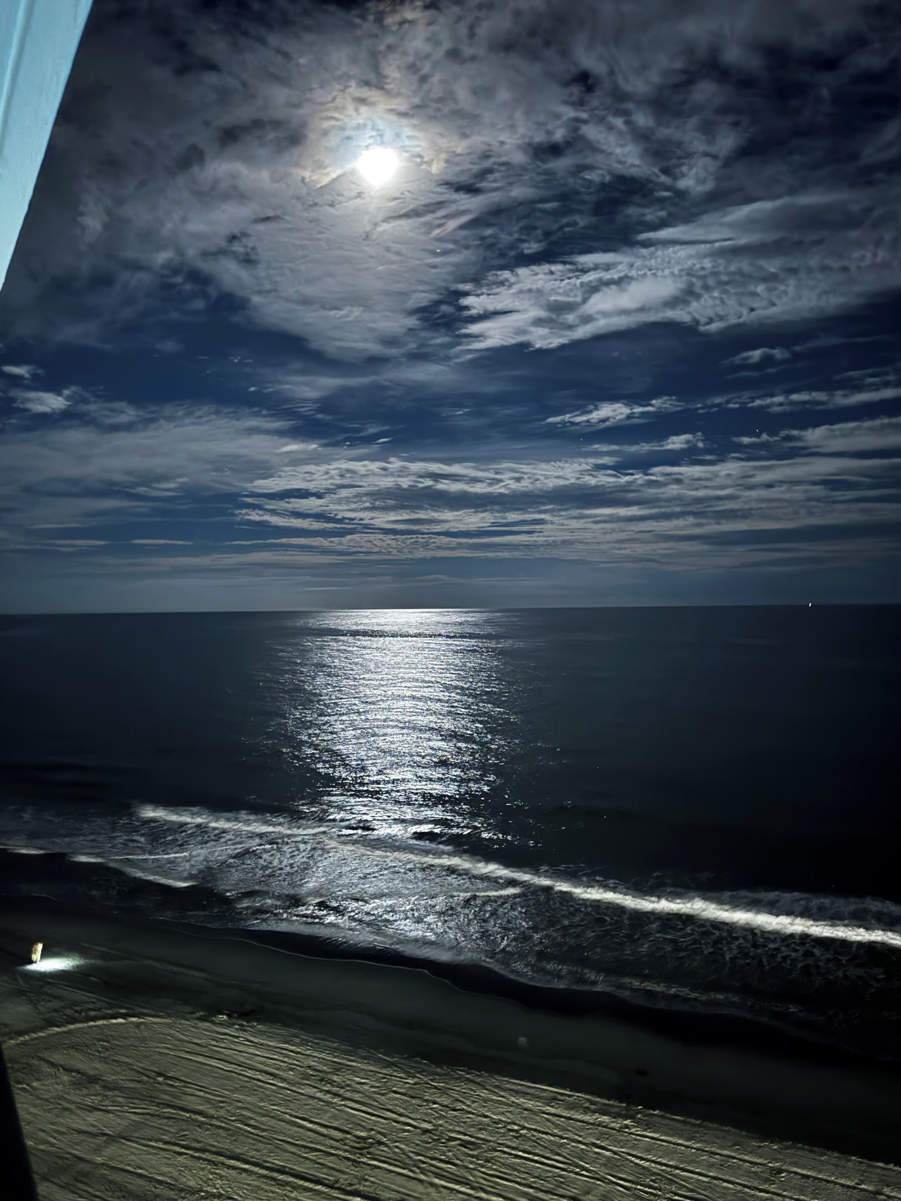 A view of the ocean with a moonlit sky and waves.