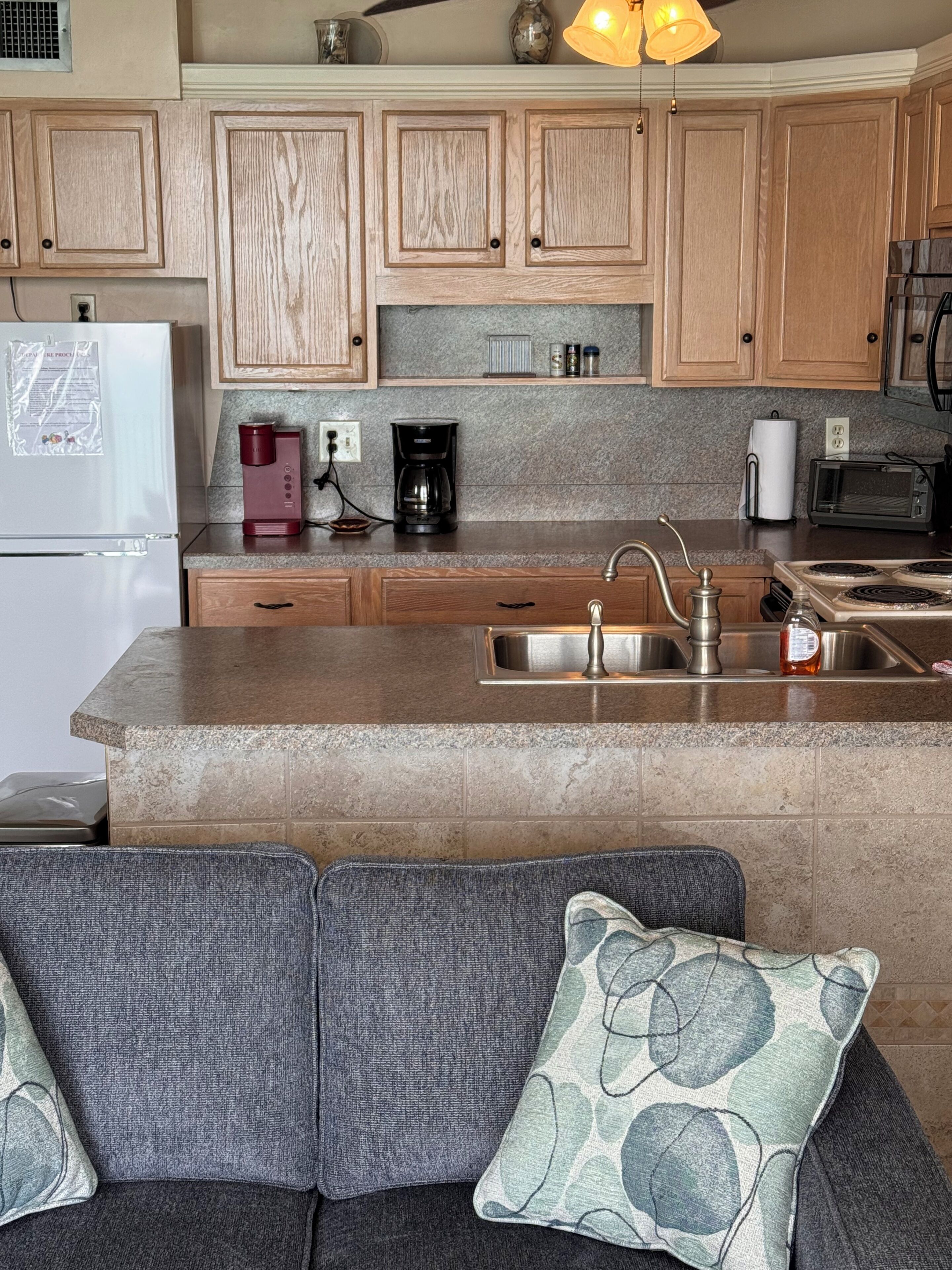 A kitchen with wooden cabinets, a granite countertop, a built-in sink, a coffee maker, and a microwave.