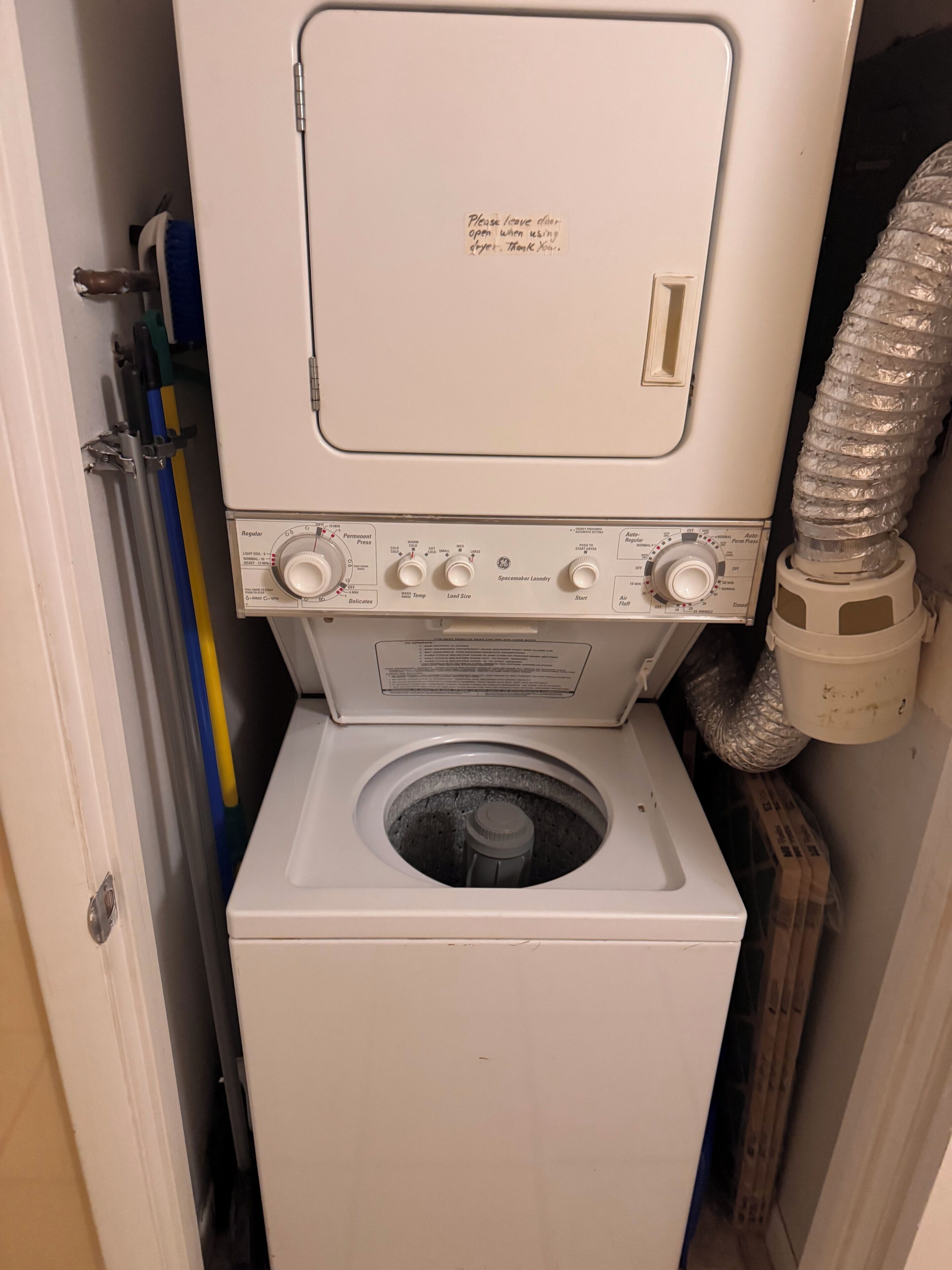 Een compacte was- en droogcombinatie met een voorlader wasmachine en een droogtrommel met bovenlader.
