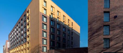 A modern multi-story hotel with a flat facade, large windows, and a brick section on the right.