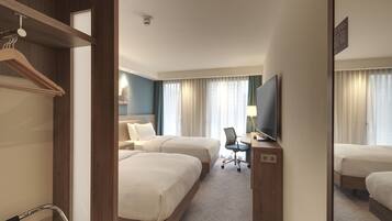 A hotel room with two beds, a desk with a chair, a TV, and a mirror.