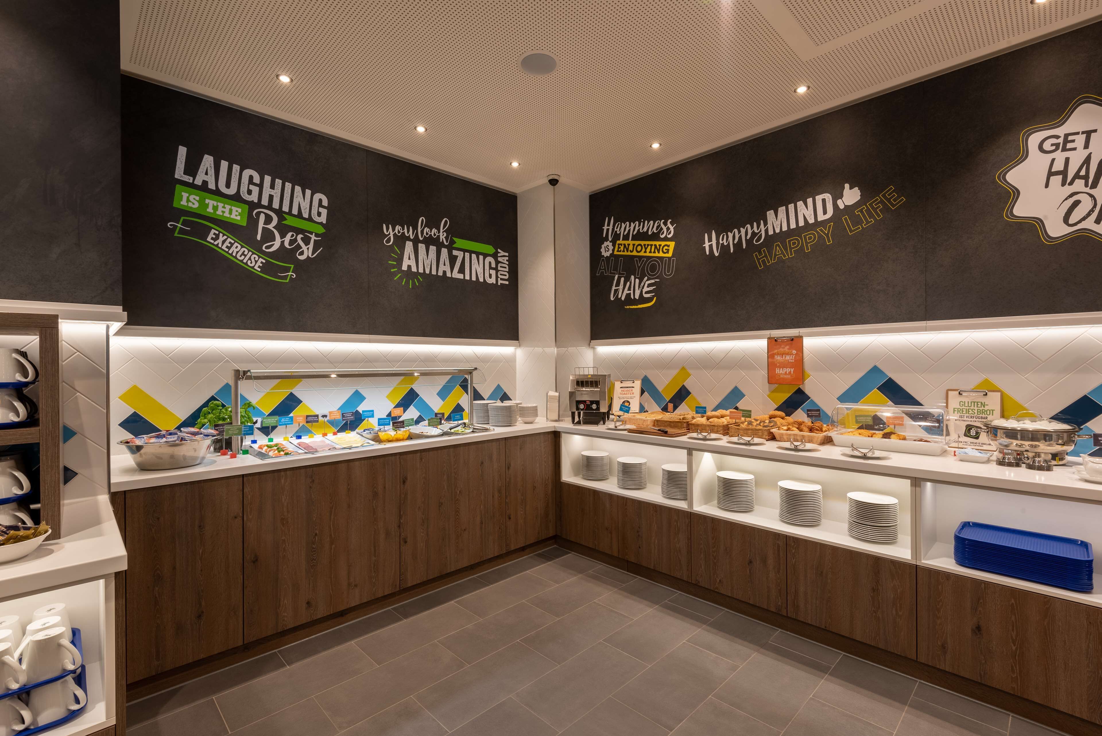 A modern breakfast area with motivational wall art, a buffet counter, and neatly arranged food and drink stations.