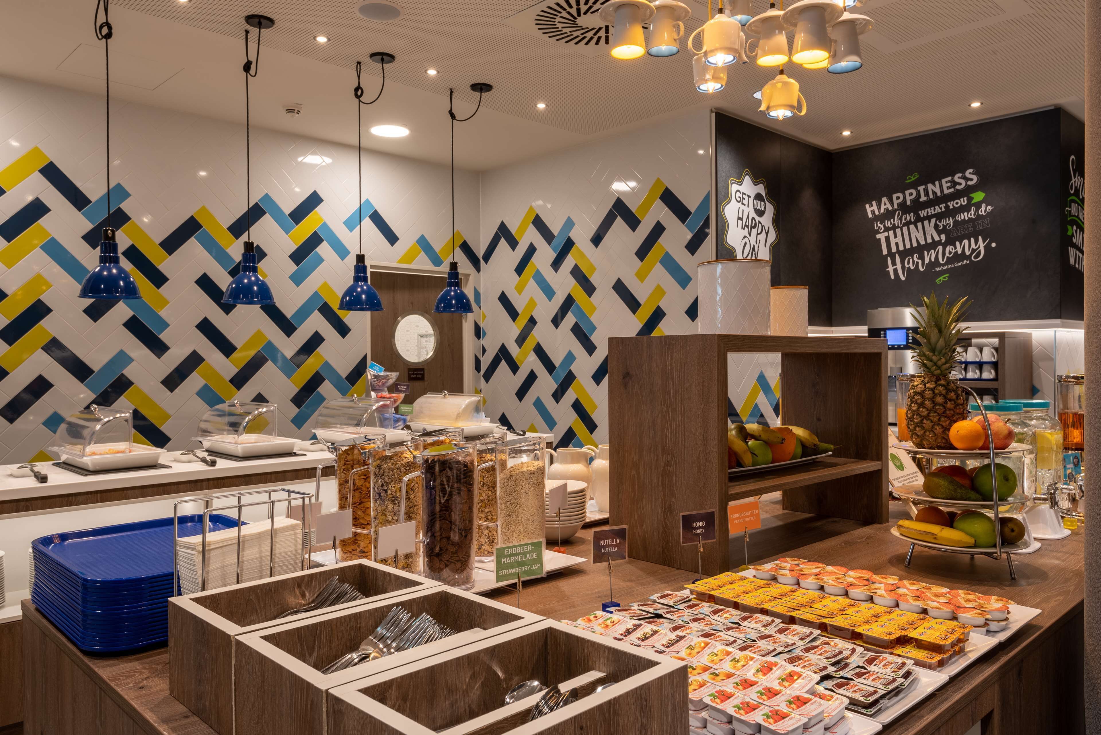 A buffet area with various food options, including fruits and desserts, and a wall with motivational quotes.