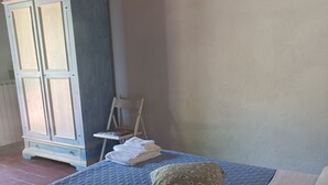A bedroom with a bed, a chair, a wardrobe, and a painting on the wall.