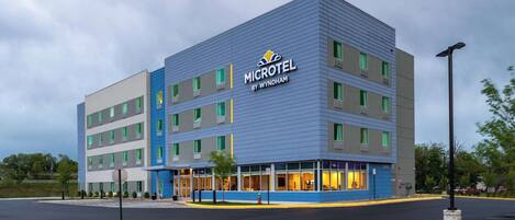 Un moderno hotel Microtel con facciata blu e grigia, diversi piani e un ingresso ben illuminato.
