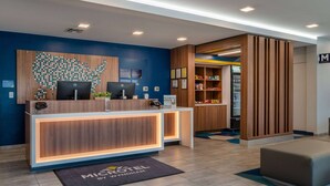 A hotel reception area with a wooden reception desk, two computers, a map of the USA on the wall, and a small plant on the desk. - Microtel Inn & Suites by Wyndham Winchester (Winchester)