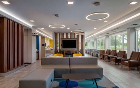 A modern lobby with a seating area, a flat-screen TV, and a large window offering a view of the outdoors.