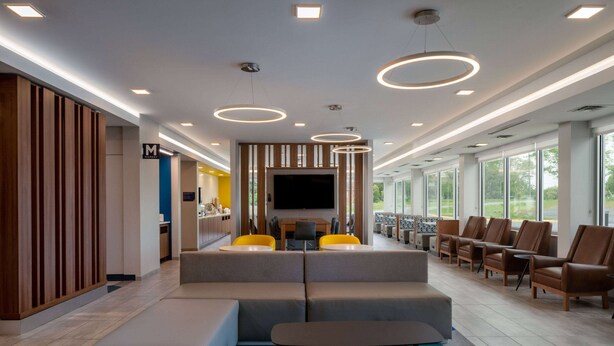 A modern lobby with a seating area, a flat-screen TV, and a large window offering a view of the outdoors. - Microtel Inn & Suites by Wyndham Winchester (Winchester)