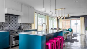 Una cucina moderna con isola centrale, elettrodomestici in acciaio inossidabile e mobili in tonalità blu brillante.