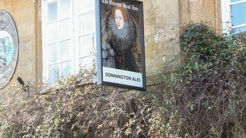Une enseigne pour «
The Queens Head Inn », avec un portrait et l’inscription «
DONNINGTON ALES » en dessous.
