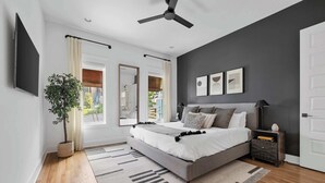 Un dormitorio moderno con una cama grande, un ventilador de techo, una planta en maceta y vistas al exterior.