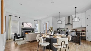 Una cocina moderna con armarios blancos, un comedor con mesa redonda y una chimenea.