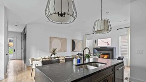 Una cocina moderna con una isla grande, electrodomésticos de acero inoxidable e iluminación colgante.