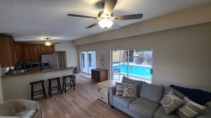 A spacious living area with a pool, a kitchen with wooden cabinets, and a ceiling fan. - 3 bedroom private vacation home in merritt island (Merritt Island)