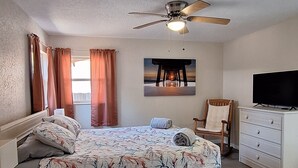 A bedroom with a bed, a ceiling fan, a chair, a dresser, and a television. - 3 bedroom private vacation home in merritt island (Merritt Island)