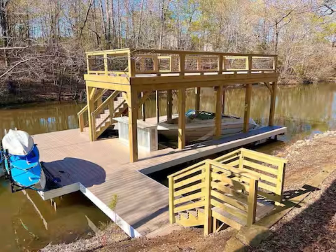 A wooden dock extending into a body of water, with a covered seating area and a small staircase leading up to it.