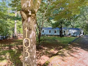 Situated in a wooded area, this single-story house offers a tranquil setting surrounded by a well-maintained lawn and trees.