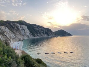 A coastal landscape with cliffs, a beach, and boats on the water.