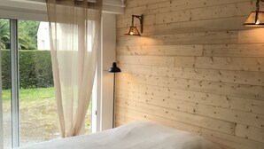 Ein Schlafzimmer mit einem großen Bett, einer Stehlampe und einer Holzwand.