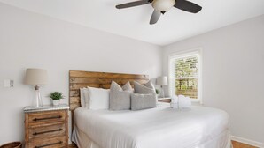 Un dormitorio con una cama grande, cabecera de madera, mesitas de noche y un ventilador de techo.