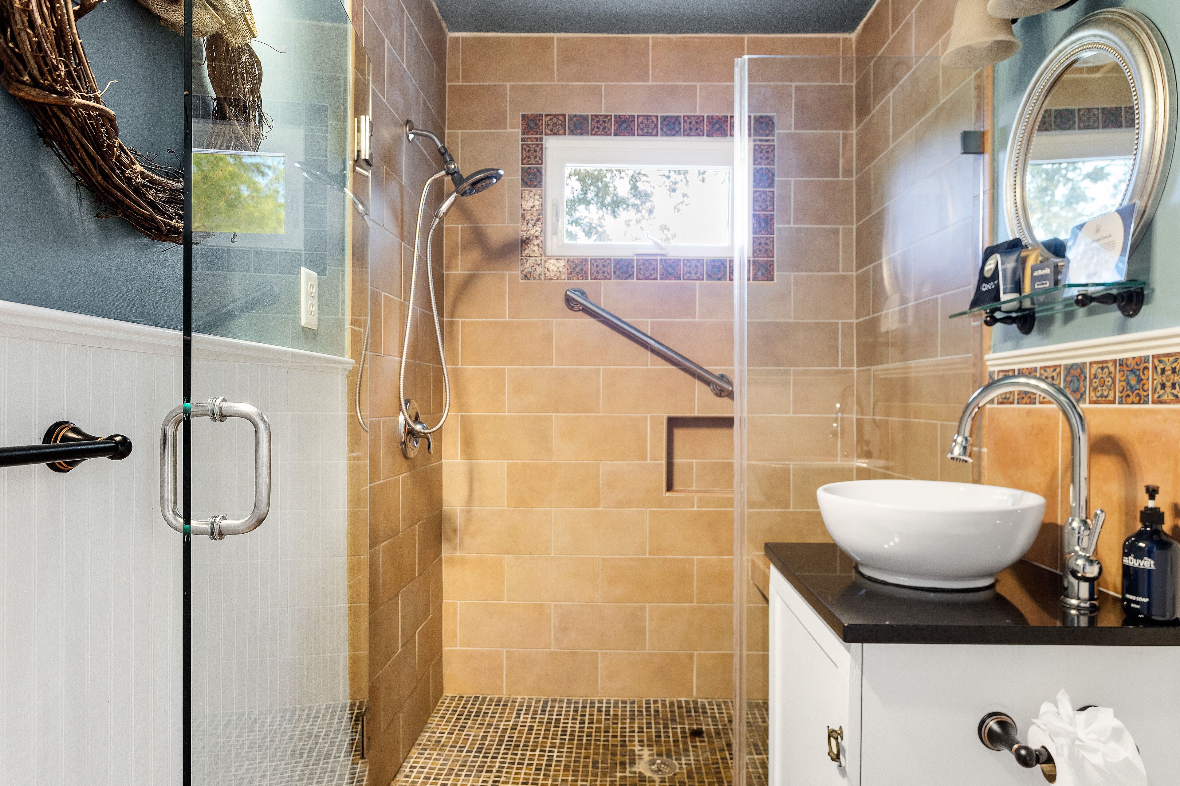 A bathroom with a glass shower enclosure, a white sink, and a mirror above it.