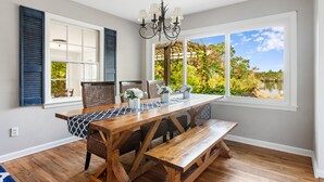 Un comedor con una mesa de madera, bancos y una araña.