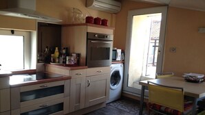 A compact kitchen with a washing machine, a microwave, and a stove. - Charming duplex, 25m2 roof terrace in the center of the old village, wifi (Collioure)