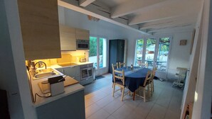 Una cocina moderna con comedor, que cuenta con una isla central, electrodomésticos integrados y vistas al exterior.