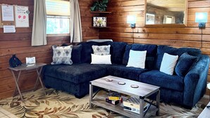 A cozy cabin-style room with a wooden ceiling, a sectional sofa, a small coffee table, and a rug. - Beautiful country views and wildlife. Less than 2 miles from downtown. (Point Pleasant)