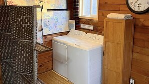 A laundry room with a washing machine, dryer, and a wooden cabinet. There is a clock on the wall and a window with curtains. - Beautiful country views and wildlife. Less than 2 miles from downtown. (Point Pleasant)