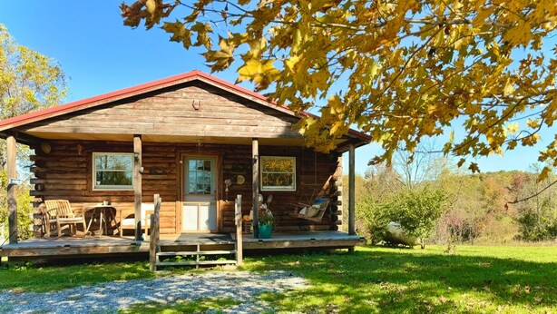 A rustic log cabin with a porch, a small deck, and a grassy yard. - Beautiful country views and wildlife. Less than 2 miles from downtown. (Point Pleasant)