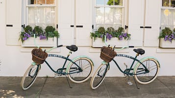 Dos bicicletas antiguas estacionadas frente a un edificio con jardineras florales en los alféizares de las ventanas.