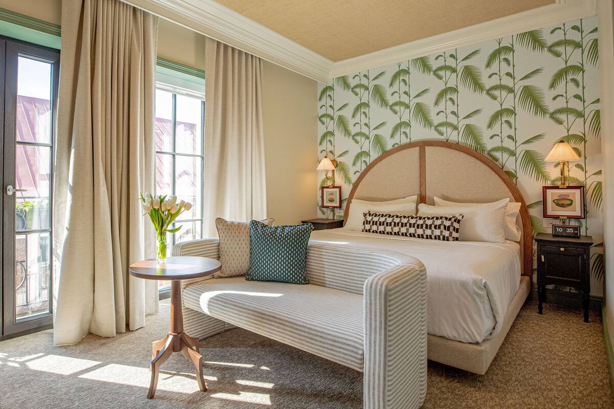 Una habitación de hotel con cama, sofá, una mesita y una ventana con cortinas.