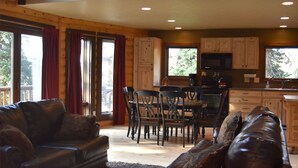 A spacious living area with a high ceiling, wooden beams, and a balcony with a railing.