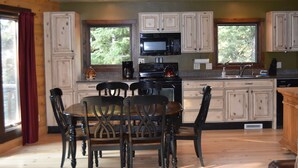 A kitchen with wooden cabinets, a dining table with chairs, a microwave, and a stove.
