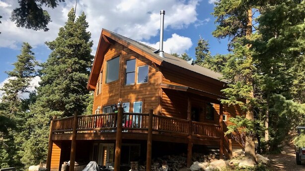 A wooden cabin with a balcony, surrounded by trees.