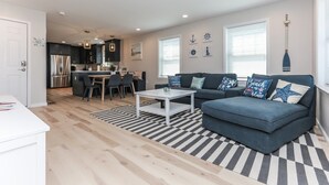 Een moderne woonkamer met een bank, salontafel en een eethoek.