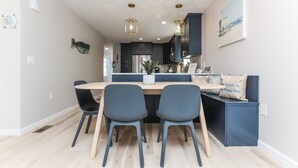 Een moderne keuken met donkere kastjes, een houten eiland en twee stoelen.
